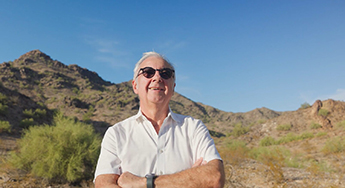 Osvaldo Sala standing cross-armed in the desert with mountain in bckground