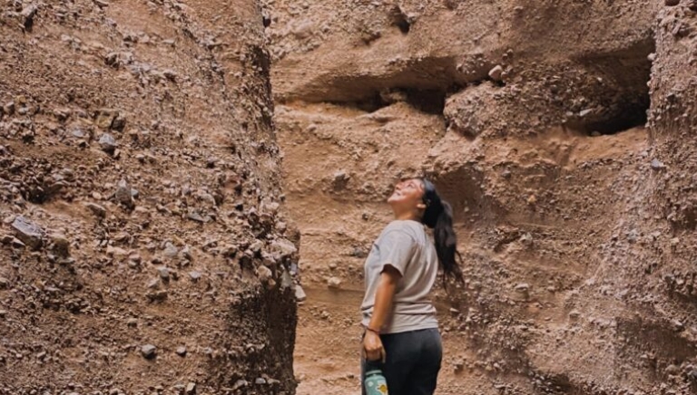 Woman standing in the bottom of a gorge looking up to the top.