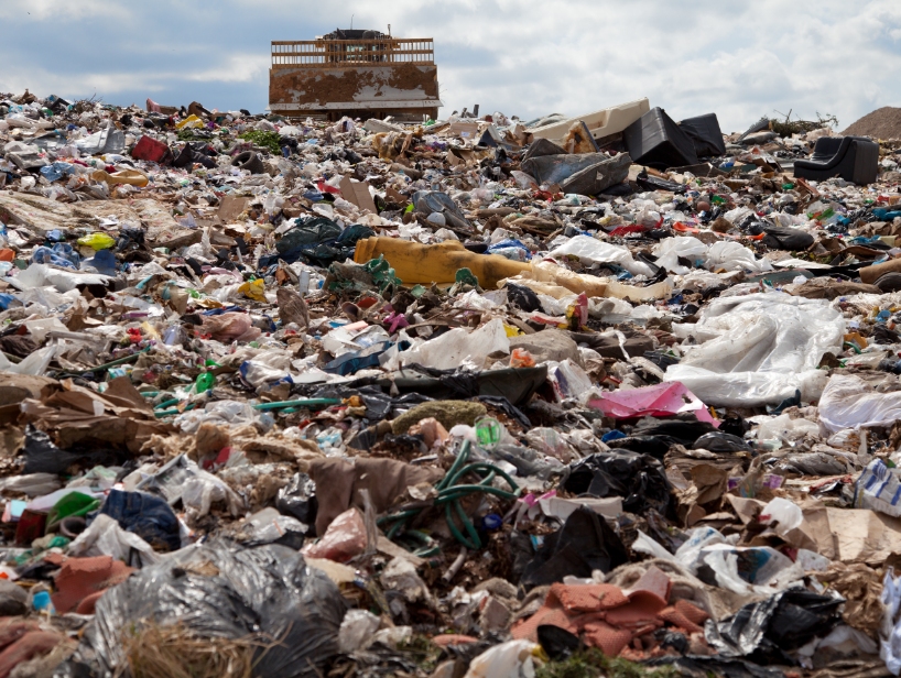 Garbage in a landfill with bulldozer on top of pile.