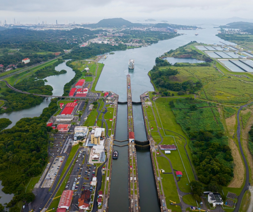 Aerial view of a canal with residential and commercial development, vibrant green trees and grass along the shores.