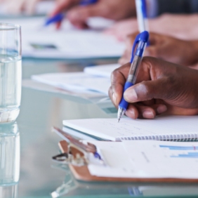 Close-up of hands holding pens and taking notes