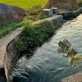 A winding path with a hill on the left side and a river on the right.